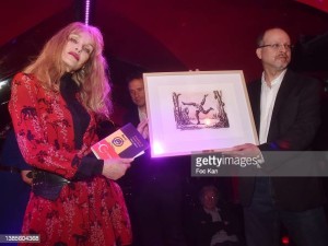 PARIS, FRANCE - MARCH 15: Arielle Dombasle gives a drawing by Roland Topor to Mikael Hirsch, Prix Castel Du Roman De La Nuit awarded writer, during the Prix Castel 2022 Du Roman De La Nuit award ceremony at Castel Club on March 15, 2022 in Paris, France. (Photo by Foc Kan/WireImage)